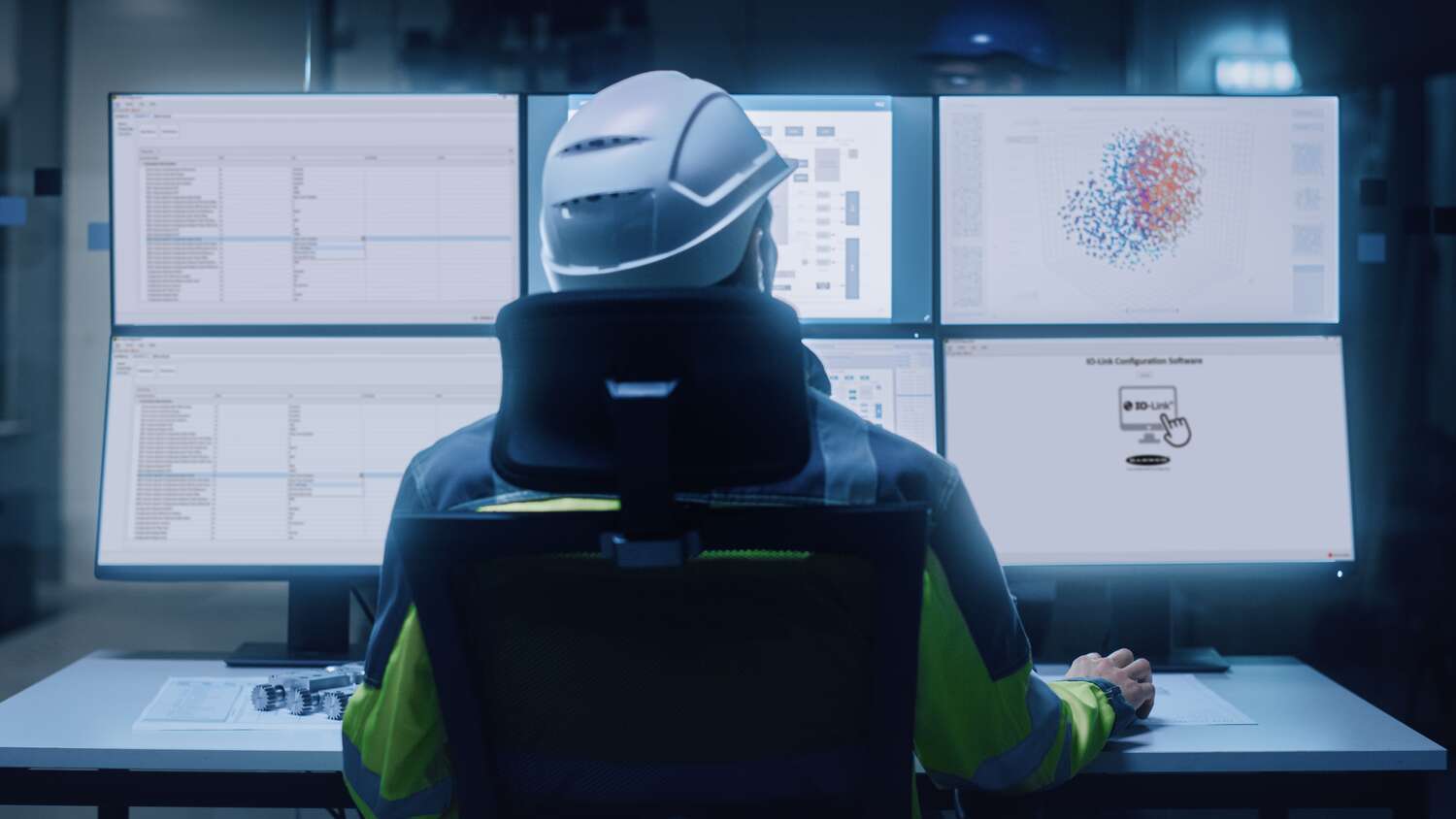 Engineer sits at a table with various computer screens and analyzes data in Banner IO-Link Configuration Software